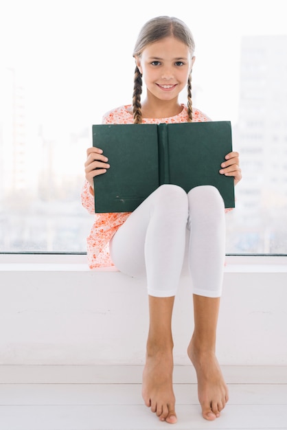 Bella ragazza felice in posa con un libro