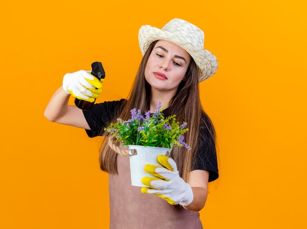 Bella ragazza giardiniera impressionata che indossa uniforme e cappello da giardinaggio