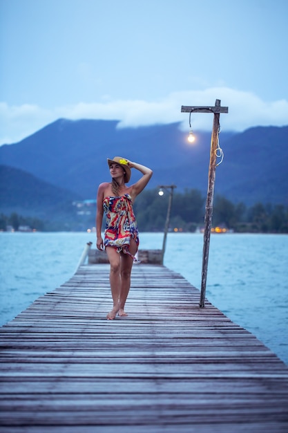 bella ragazza in cappello sul molo in legno più lungo la sera a Koh Chang, Thailandia