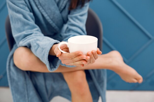 Bella ragazza in piedi in uno studio in un accappatoio blu