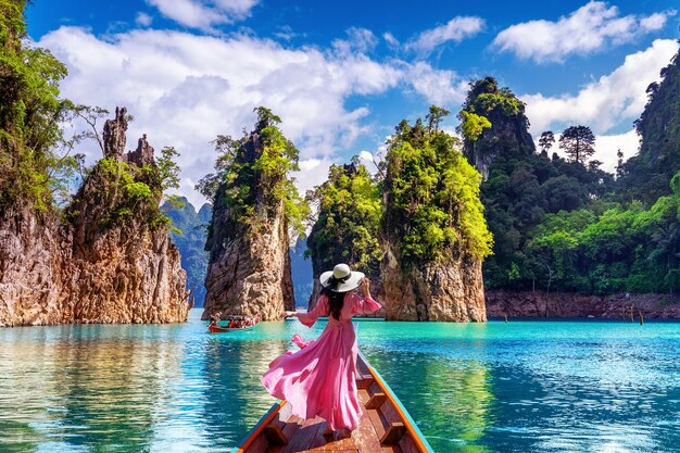 Bella ragazza in piedi sulla barca e guardando alle montagne nella diga di Ratchaprapha al Parco Nazionale di Khao Sok, Provincia di Surat Thani, Thailandia.