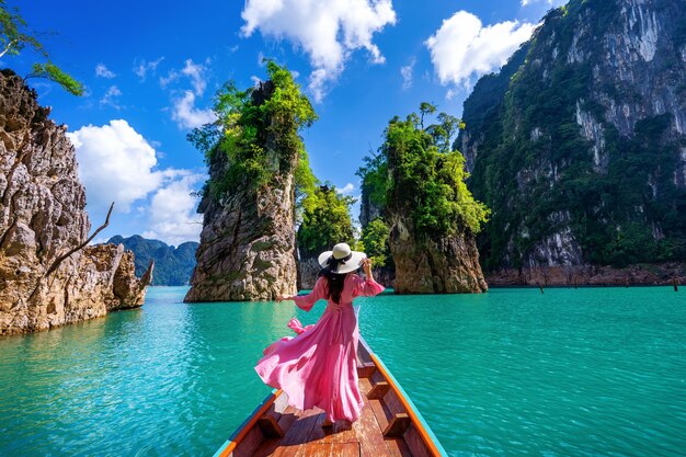 Bella ragazza in piedi sulla barca e guardando alle montagne nella diga di Ratchaprapha al Parco Nazionale di Khao Sok, Provincia di Surat Thani, Thailandia.