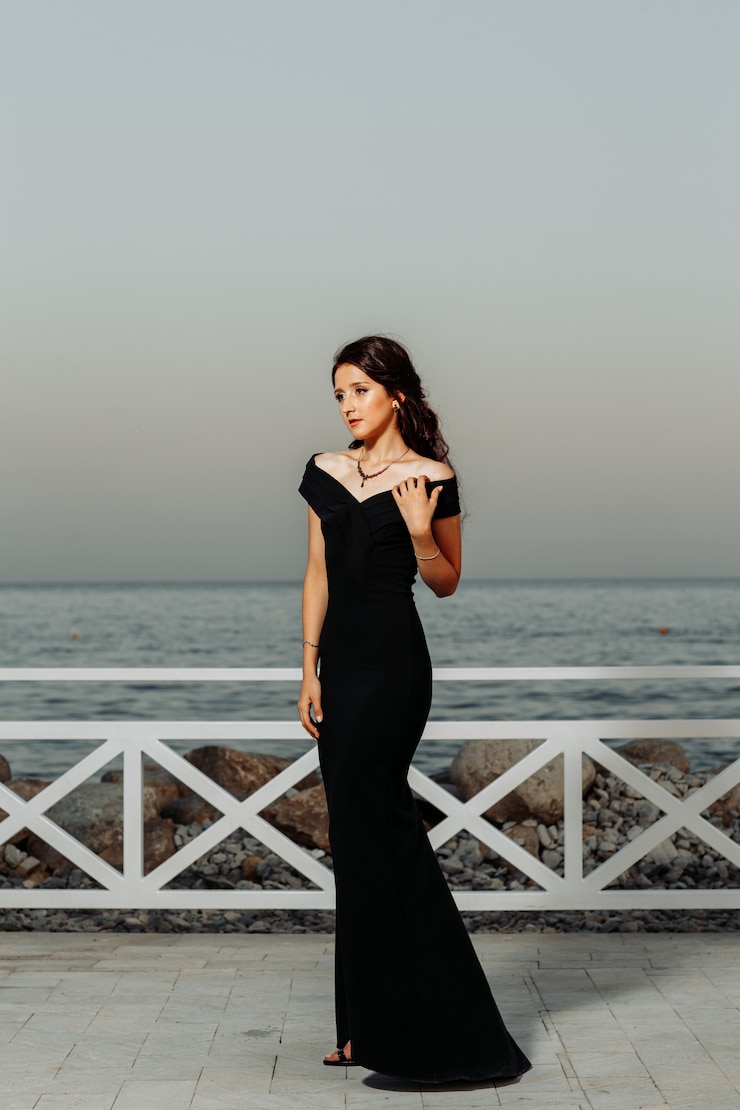 Foto gratuito bella ragazza in piedi vicino al mare in abito lungo nero durante il giorno