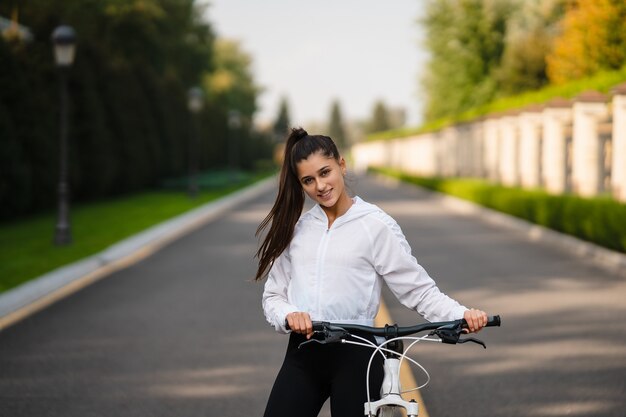 Bella ragazza in posa in bicicletta bianca. Cammina nella natura. Uno stile di vita sano.