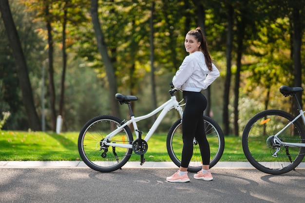 Bella ragazza in posa in bicicletta bianca. Cammina nella natura.