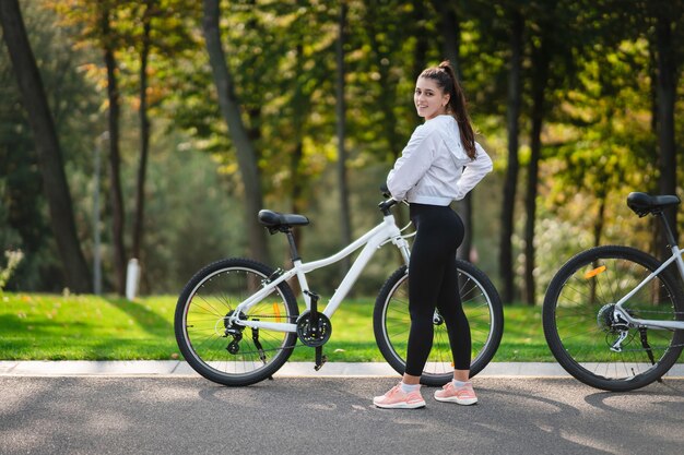 Bella ragazza in posa in bicicletta bianca. Cammina nella natura.