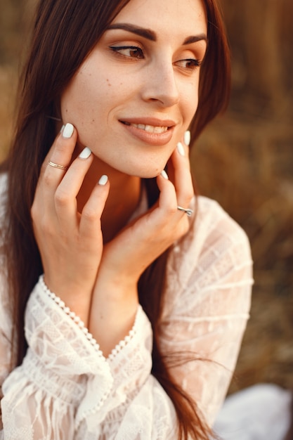 Bella ragazza in un abito bianco. Donna in un campo di grano autunnale.