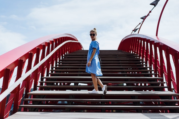 bella ragazza in un abito blu in posa sul ponte