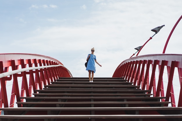 bella ragazza in un abito blu in posa sul ponte