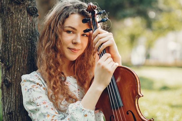 Bella ragazza in un parco estivo con un violino