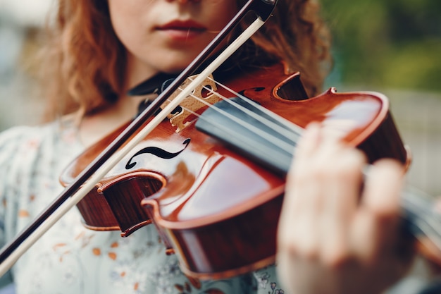 Bella ragazza in un parco estivo con un violino