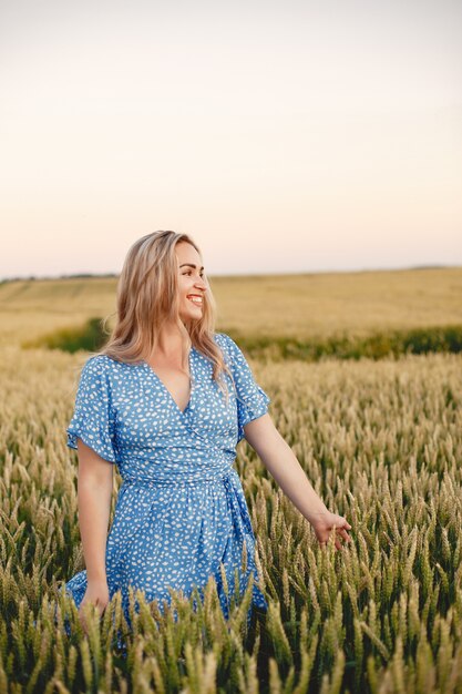 Bella ragazza in un vestito blu. Donna in un campo estivo.