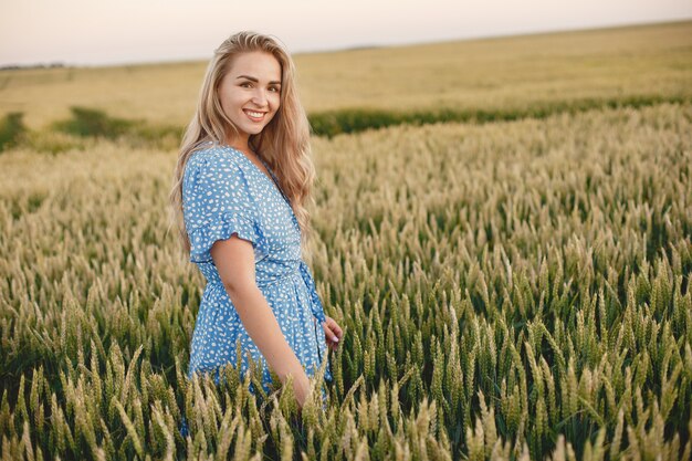 Bella ragazza in un vestito blu. Donna in un campo estivo.