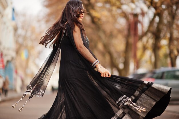 Bella ragazza indiana in abito saree nero posato all'aperto in autunno street