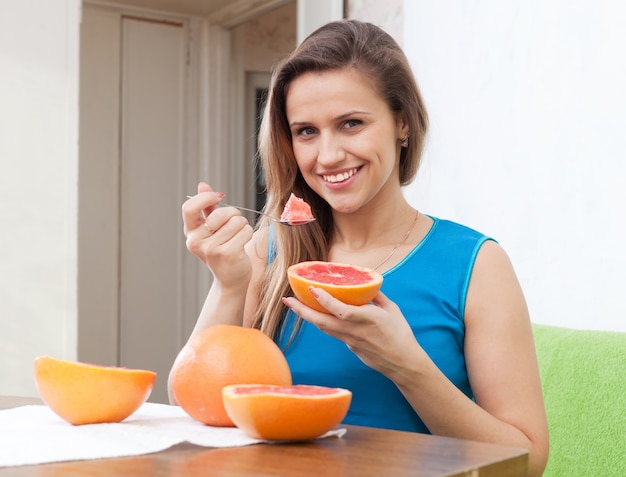 bella ragazza mangia pompelmo con un cucchiaio