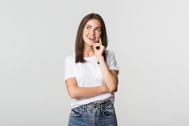 Bella ragazza premurosa e sognante che guarda nell'angolo in alto a sinistra, facendo una scelta.