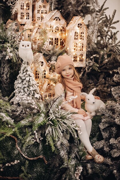 Bella ragazza scatta foto in una decorazione natalizia con molti alberi sotto la neve e luci