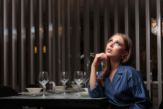 Bella ragazza seduta nella sala da pranzo e pensare