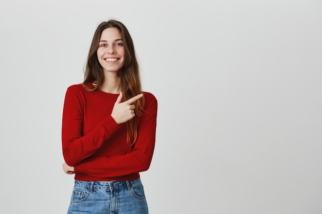 Bella ragazza sorridente che indica il dito nell'angolo in alto a destra all'insegna di promo