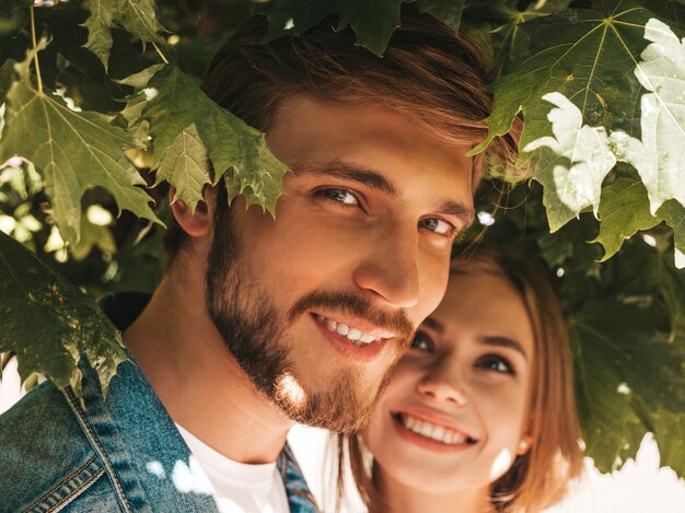 Bella ragazza sorridente e il suo ragazzo bello che posano nella via vicino all'albero.