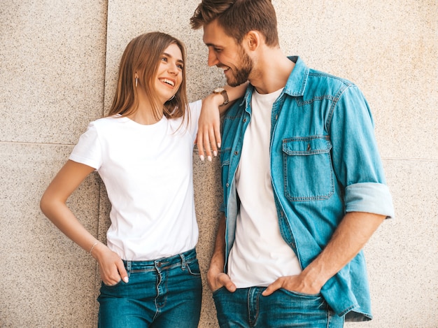 Bella ragazza sorridente e il suo ragazzo bello in abiti casual estivi. Famiglia allegra felice divertendosi sullo sfondo strada. Guardarsi l'un l'altro