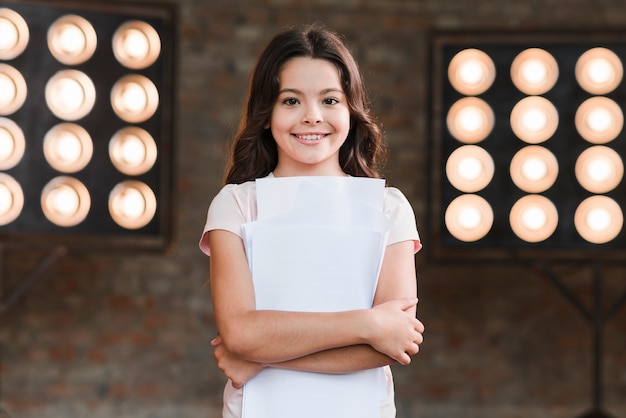 Bella ragazza sorridente in piedi davanti alla luce del palcoscenico