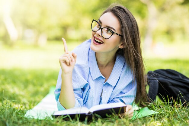 Bella ragazza teenager sognante che si trova nel parco con penna e taccuino