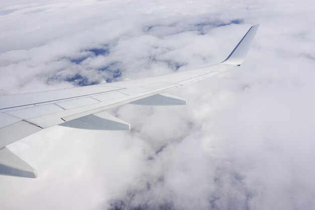 Bella ripresa del cielo pieno di nuvole e un'ala di aereo dal finestrino dell'aereo