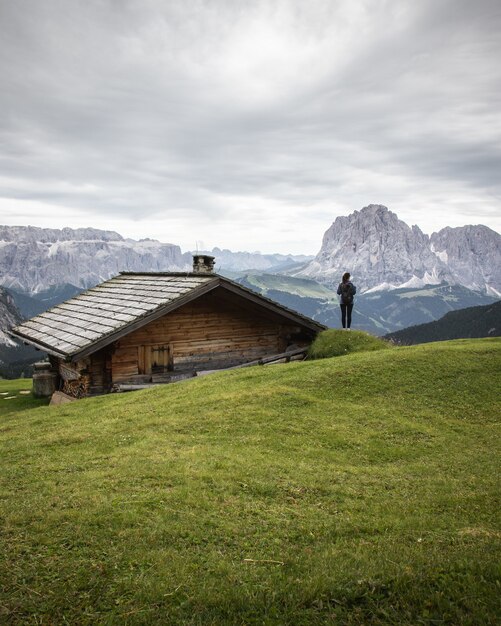 Bella ripresa di una casa in legno e di una persona nel Parco Naturale Puez-Odle a Miscì, Italia