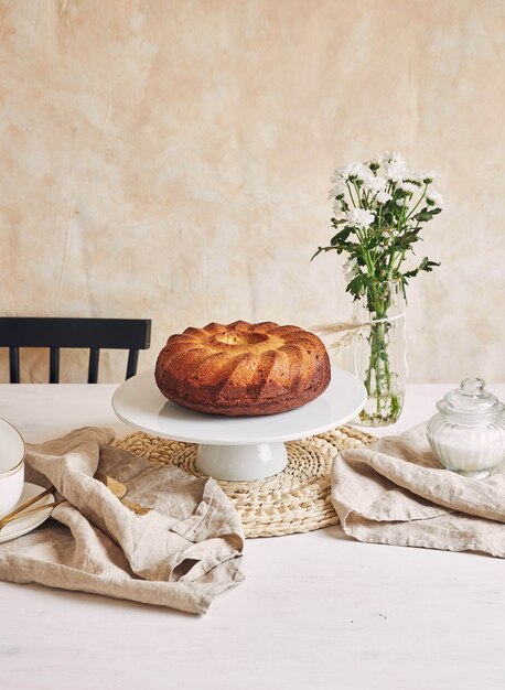 Bella ripresa di una deliziosa torta ad anelli posta su un piatto bianco e un fiore bianco vicino