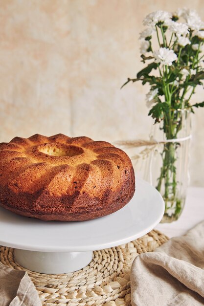 Bella ripresa di una deliziosa torta ad anelli posta su un piatto bianco e un fiore bianco vicino