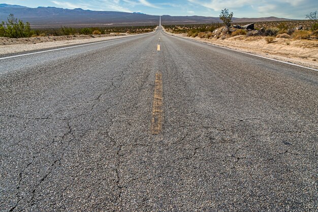Bella ripresa di una lunga strada di cemento rettilinea tra il campo del deserto
