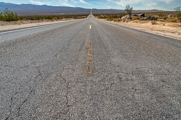 Bella ripresa di una lunga strada di cemento rettilinea tra il campo del deserto