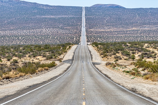 Bella ripresa di una lunga strada di cemento rettilinea tra il campo del deserto