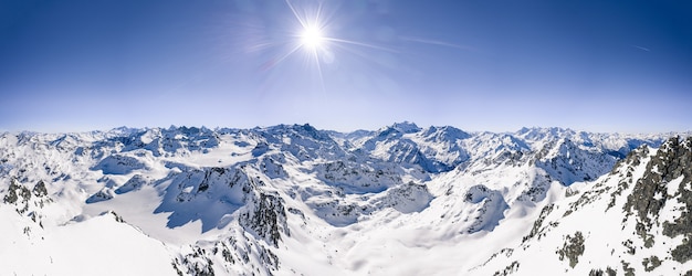 Bella ripresa panoramica delle catene montuose innevate sotto un cielo soleggiato blu chiaro