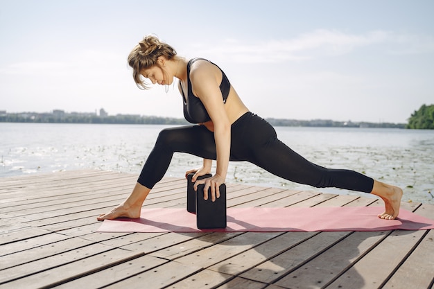 Bella signora che si allena in un parco estivo. Bruna che fa yoga. Ragazza in una tuta sportiva.