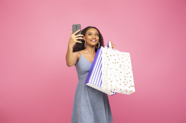 Bella signora che si fa un selfie con il telefono mentre tiene in mano alcune borse della spesa