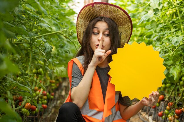 Bella signora che tiene la scheda idea e il gesto silenzioso alla serra