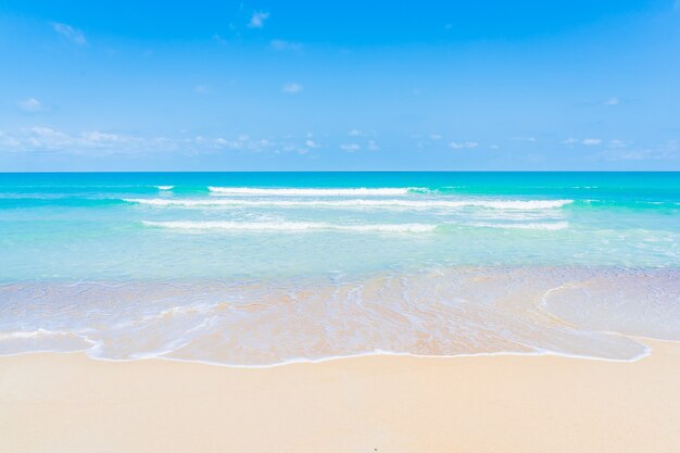 Bella spiaggia tropicale mare oceano con nuvole bianche e sfondo blu cielo per viaggio vacanza viaggio
