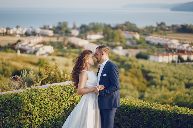 bella sposa dai capelli lunghi in abito bianco con il suo giovane a piedi nella natura