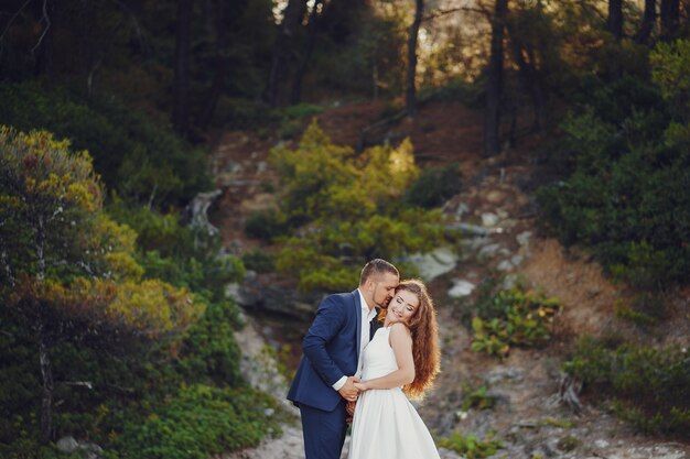 bella sposa dai capelli lunghi in abito bianco con il suo giovane a piedi nella natura