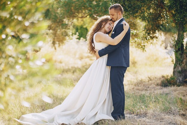 bella sposa dai capelli lunghi in abito bianco con il suo giovane a piedi nella natura