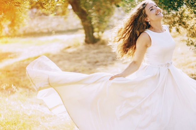 Bella sposa dai capelli lunghi in un magnifico abito bianco a piedi nella natura