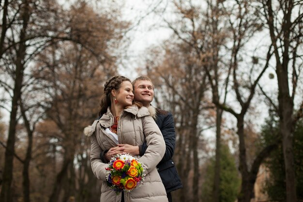 Bella sposa e sposo ucraino in abiti naturali ricamo sullo sfondo di alberi in un parco, cerimonia di nozze tradizionali