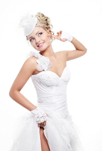Bella sposa sorridente felice in abito da sposa bianco con acconciatura e trucco luminoso