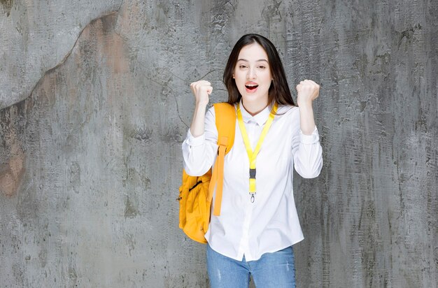Bella studentessa con zaino giallo che si sente felice. Foto di alta qualità