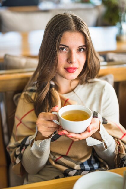 Bella tazza di tisana della holding della giovane donna