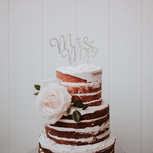 bella torta nuziale decorata con rose bianche su fondo di legno bianco