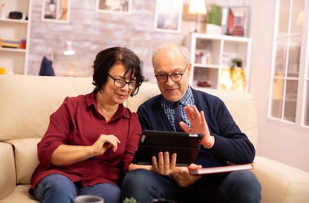 Bella vecchia coppia che utilizza una tavoletta digitale per chattare con la propria famiglia. Anziani che utilizzano la tecnologia moderna