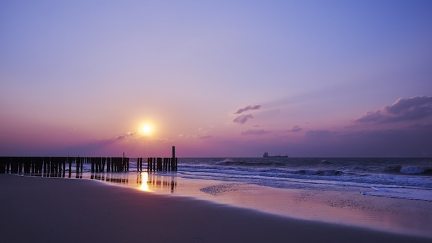 Bella vista del tramonto con nuvole viola sopra la spiaggia